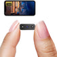 Small camera device held between two fingers with a smartphone screen displaying video footage.